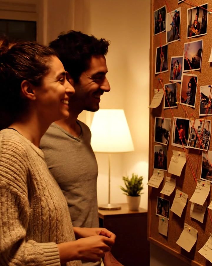 Casal diante de um quadro de cortiça cheio de pistas